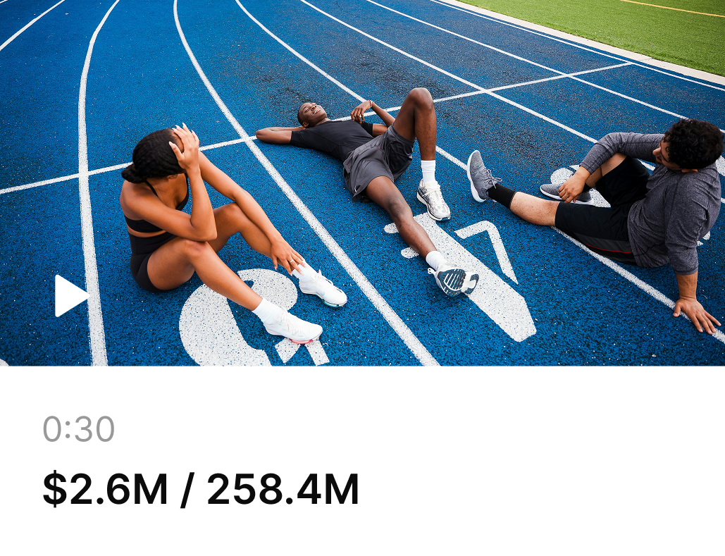 Three athletes resting on a blue running track after exercising, sitting and lying down near lane numbers 4 and 5.