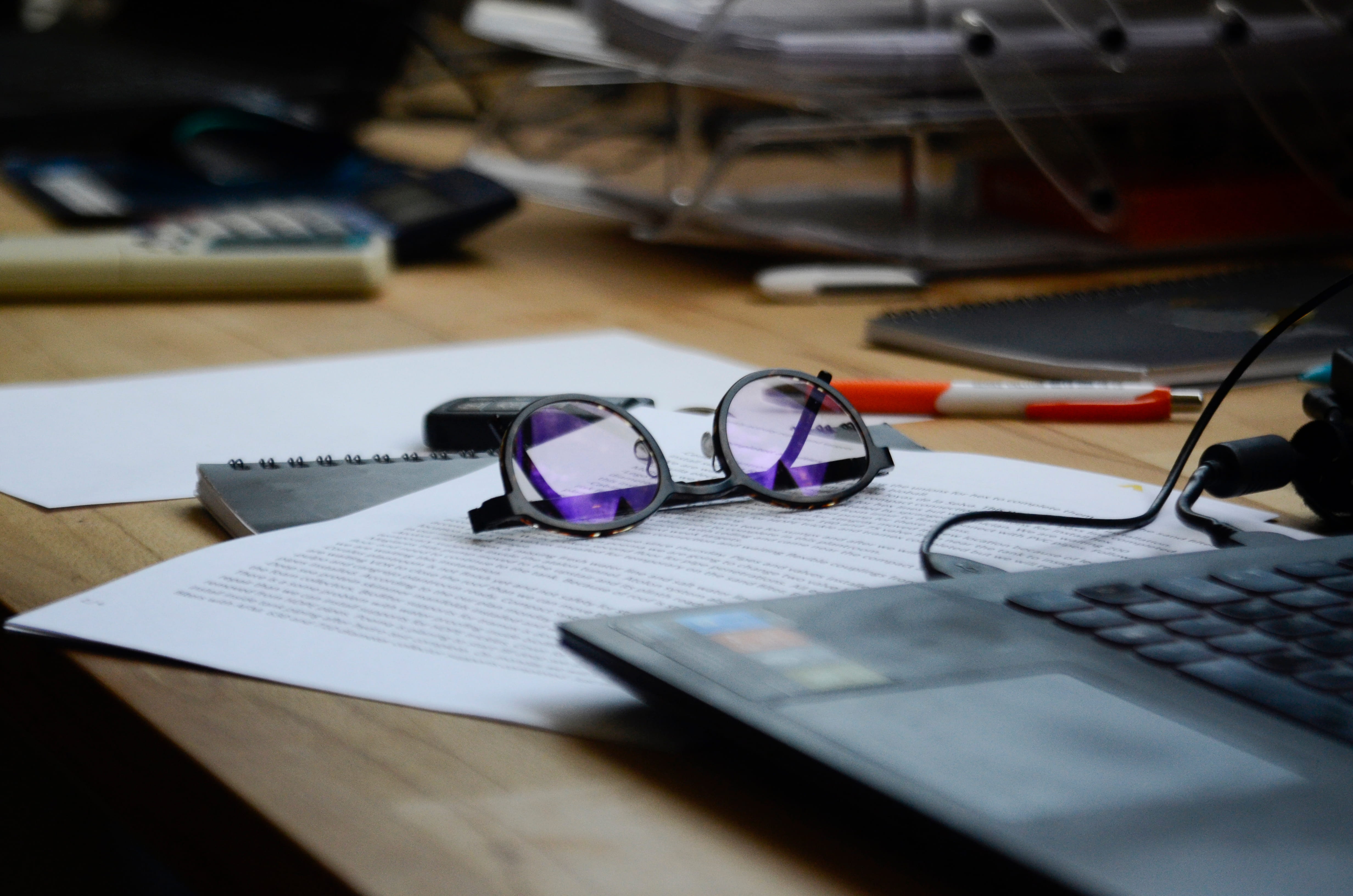 Glasses with purple lenses on typed document surrounded by office supplies and workspace items