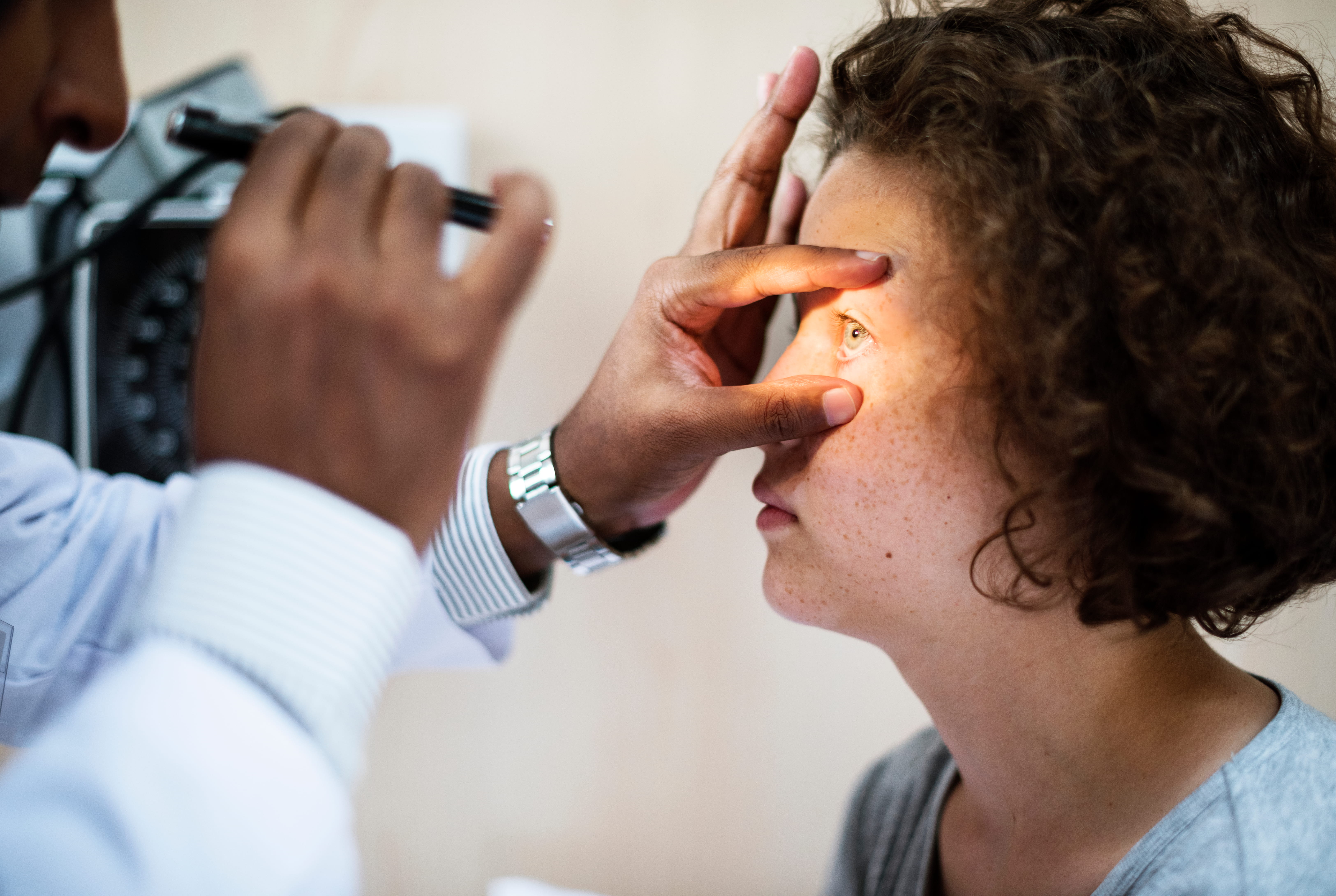Medical professional examining patient's eye with portable ophthalmoscope during vision assessment