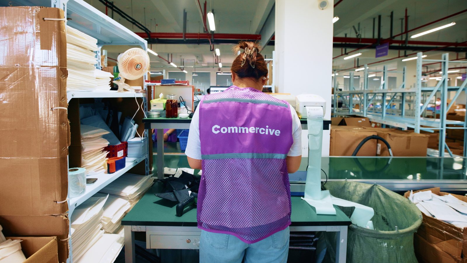 A Commercive team member weighing and labelling orders at a packing bench