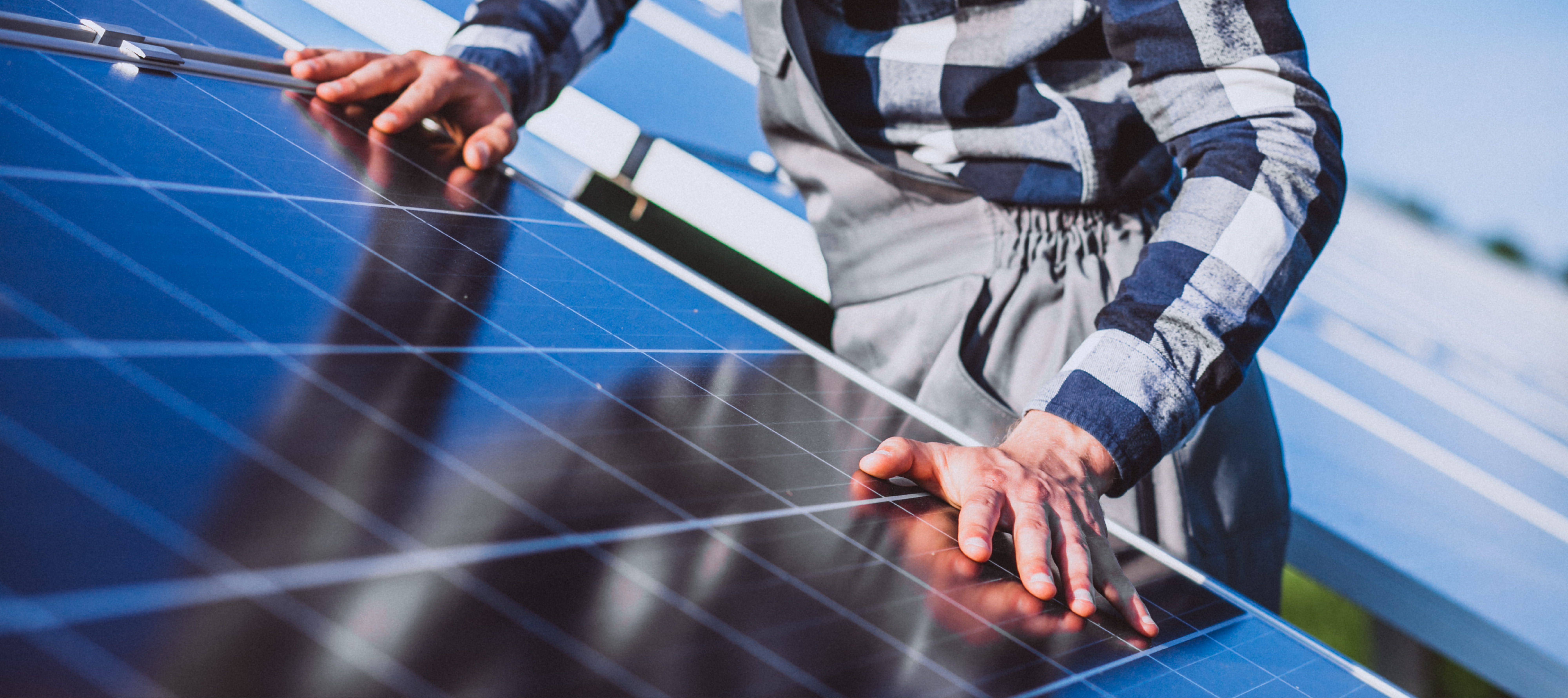 Sfeerbeeld met zonnepanelen die worden aangeraakt door man met werkkleding.