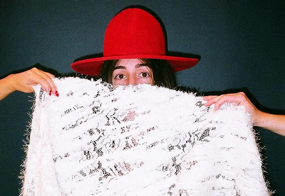 Image of a woman peeking out from behind some textiles