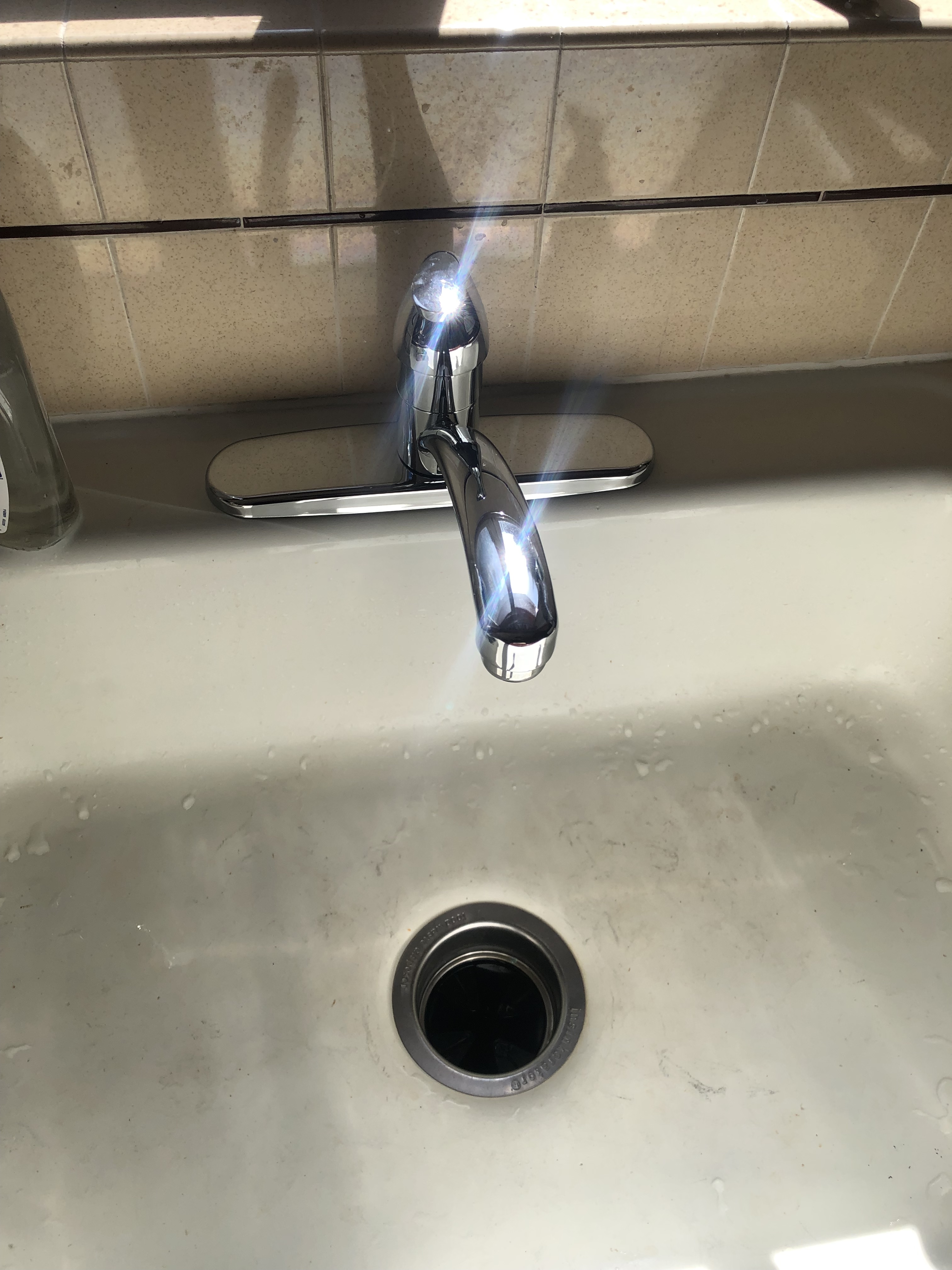 A modern bathroom featuring a glass-enclosed walk-in shower with rain showerhead on the left, a streamlined white toilet centered under a window, and a floating wooden-topped vanity with two vessel sinks and chrome faucets on the right.