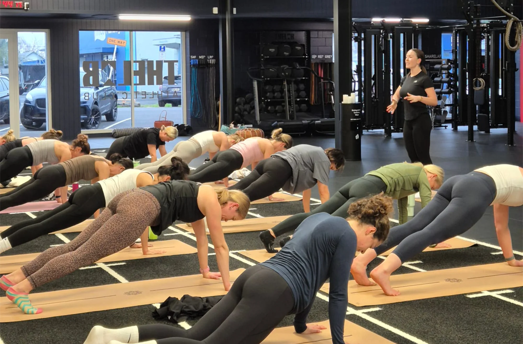 A group of women perform stretches in a gym environment