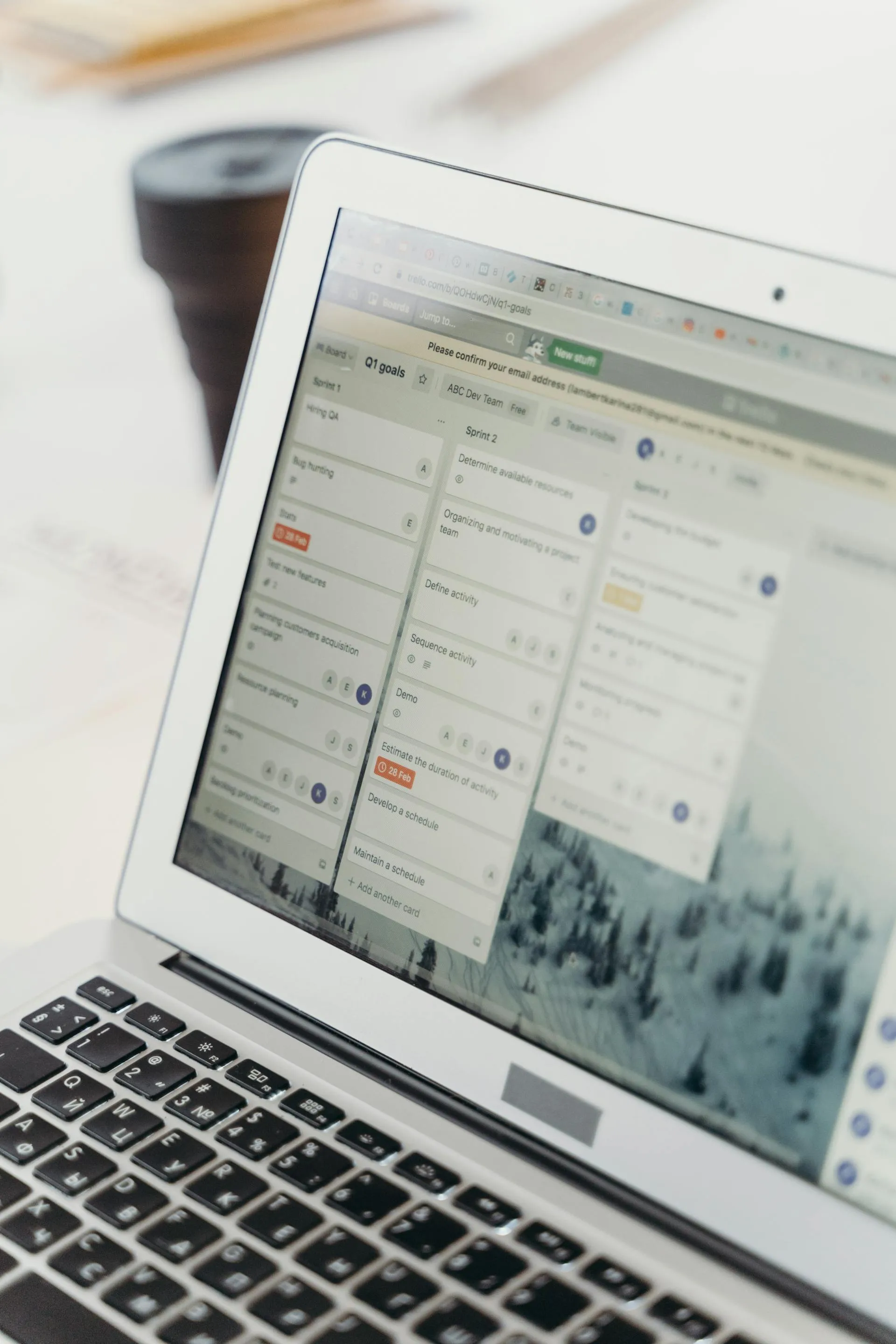 Auf dem Bildschirm eines Laptops ist eine geöffnete Projektmanagement-Software mit mehreren Aufgabenlisten und Karten zu sehen.