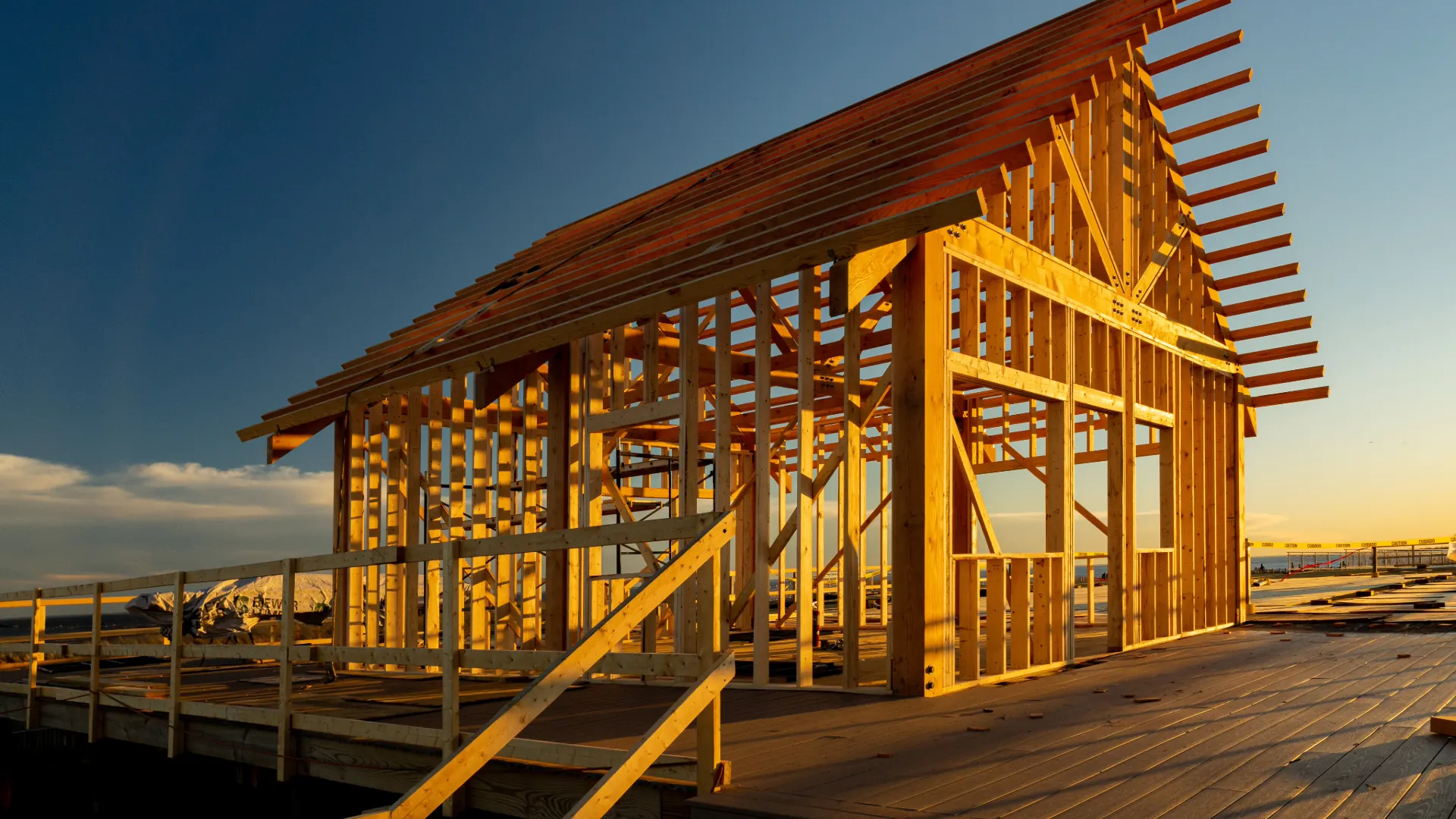 Wood framing of a house under construction against a vivid sunset sky