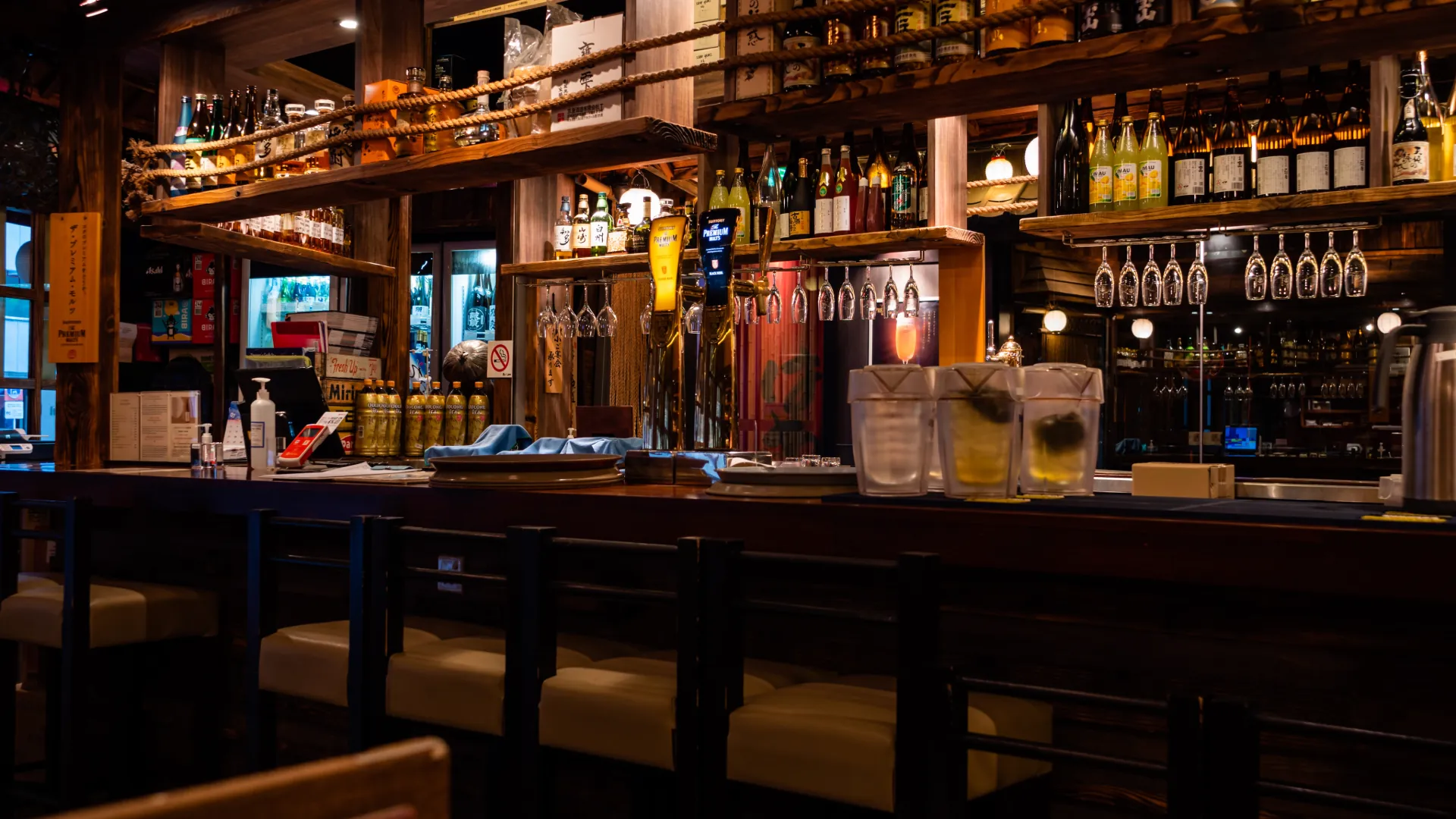 Empty bar counter lined with backlit bottles in the evening