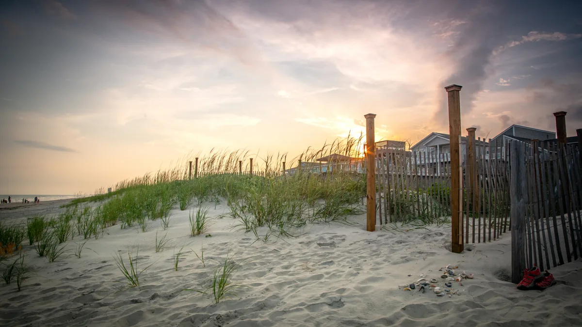Sunset through the dune fence and beach homes on Ocean Isle Beach, North Carolina