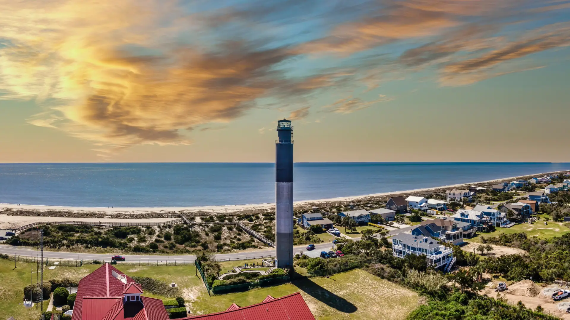 Oak Island Lighthouse and beach cottages under a colorful sky, Oak Island, North Carolina