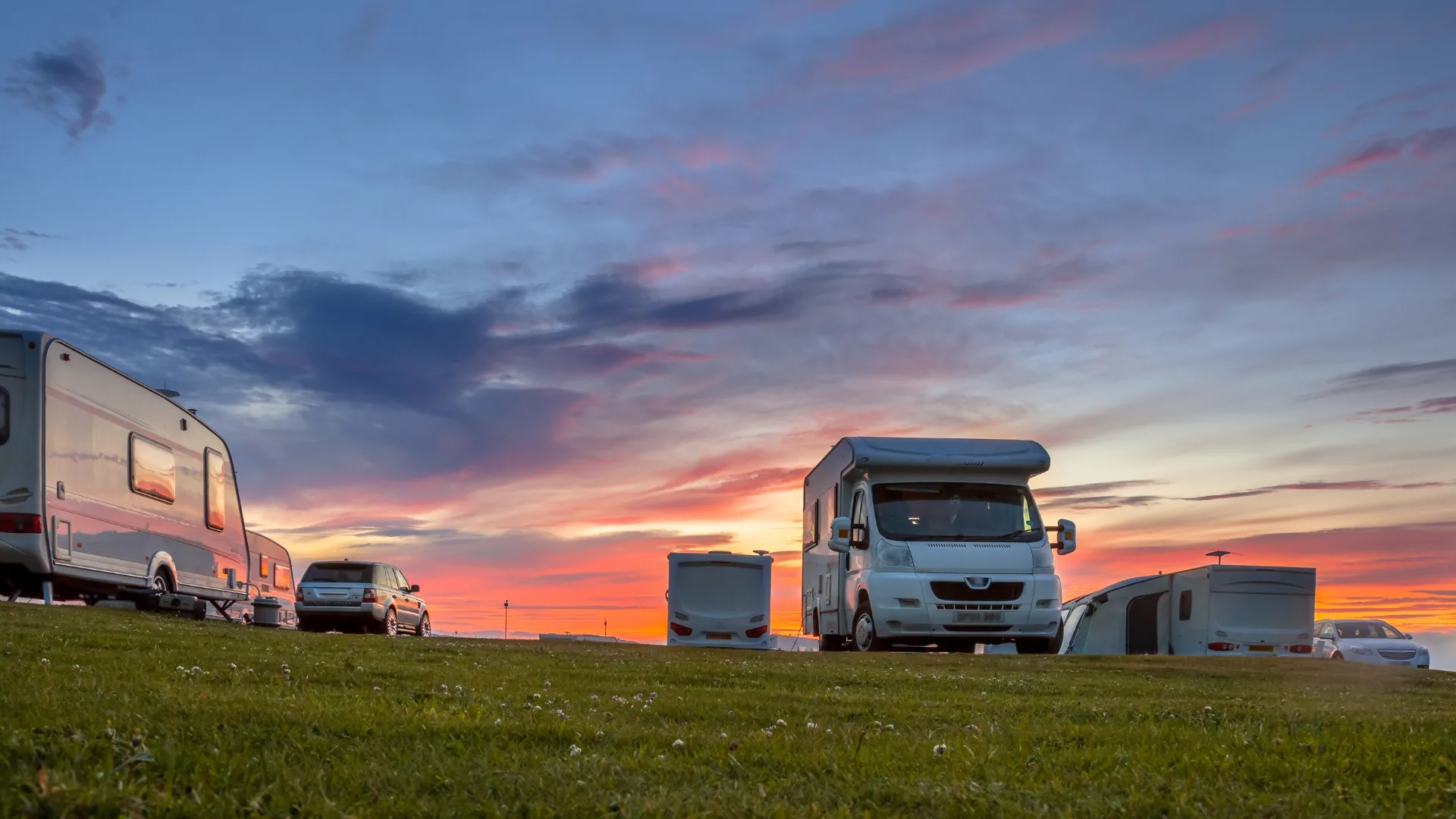 Campers and motorhomes at a campsite under a glowing evening sky