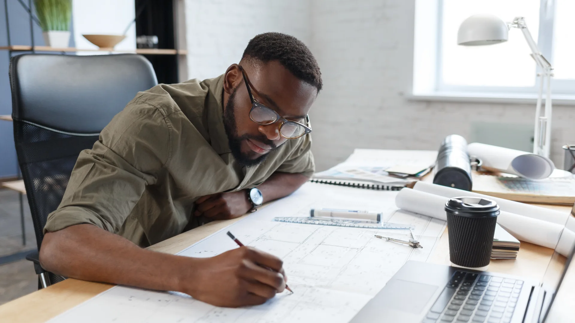 Architect working over blueprints at a bright office desk