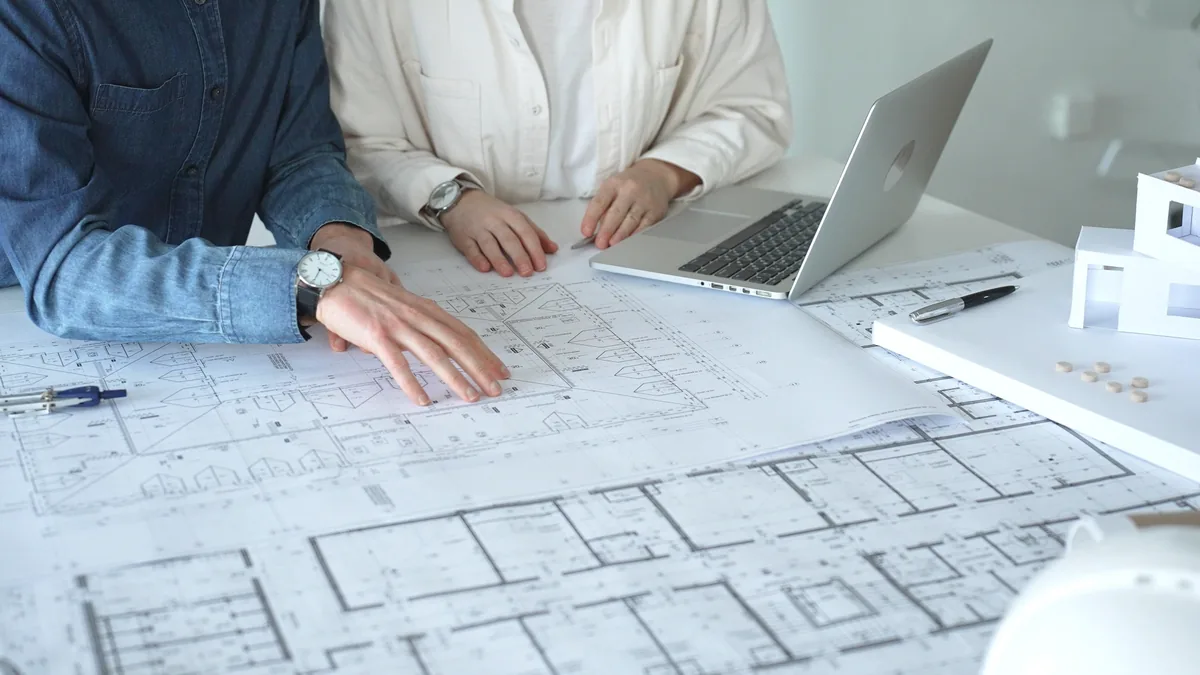 Two architects working together over blueprints and a model