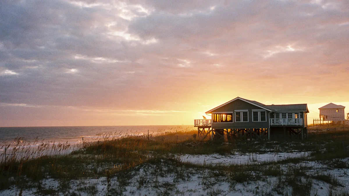 Raised beach house in the dunes with a glowing sunset over the ocean