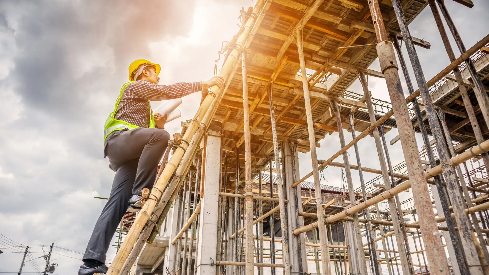 Worker climbing the wood framing of a house under construction in bright sunlight