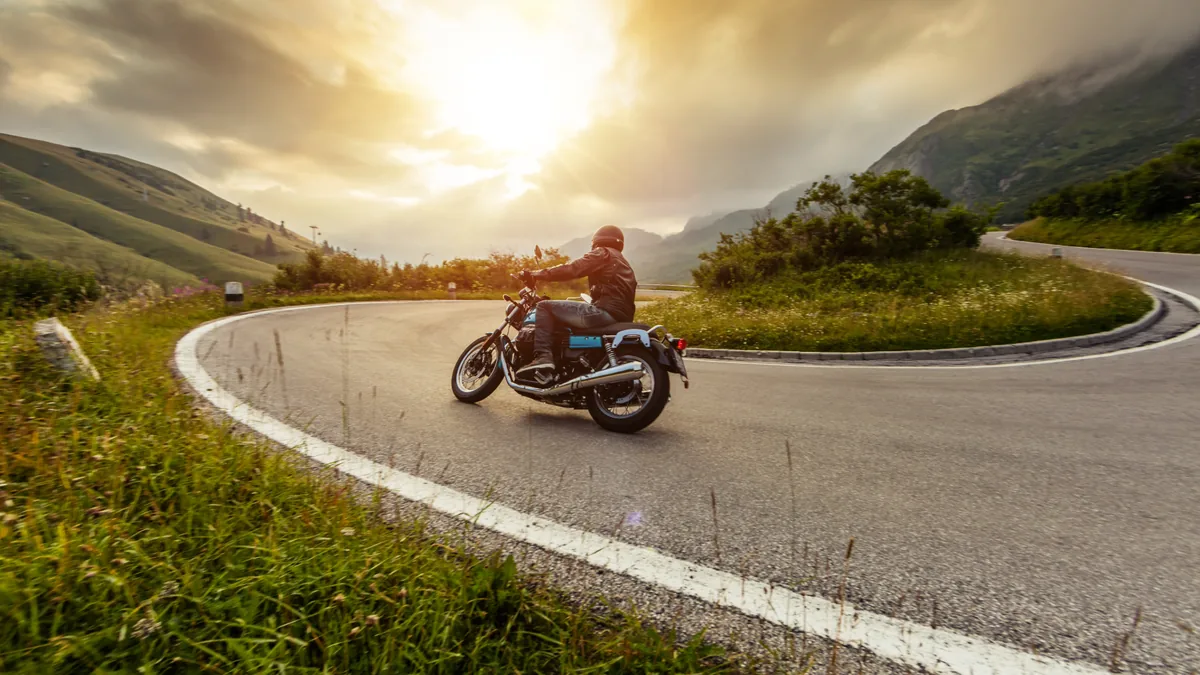 Motorcycle leaning into a sweeping curve in green mountain country