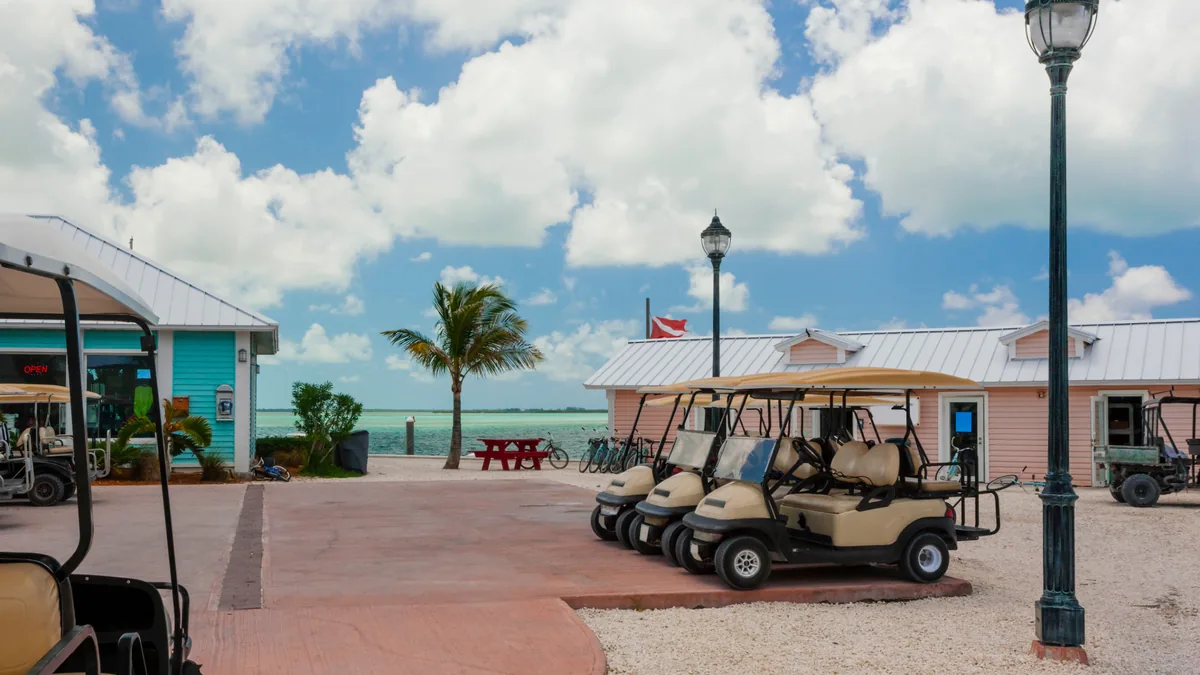 Golf carts parked along a seaside promenade with lamp posts