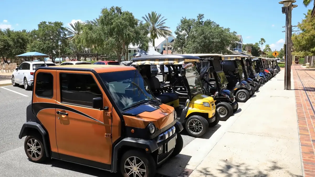 Golf carts and a low-speed vehicle parked in a row along a town street