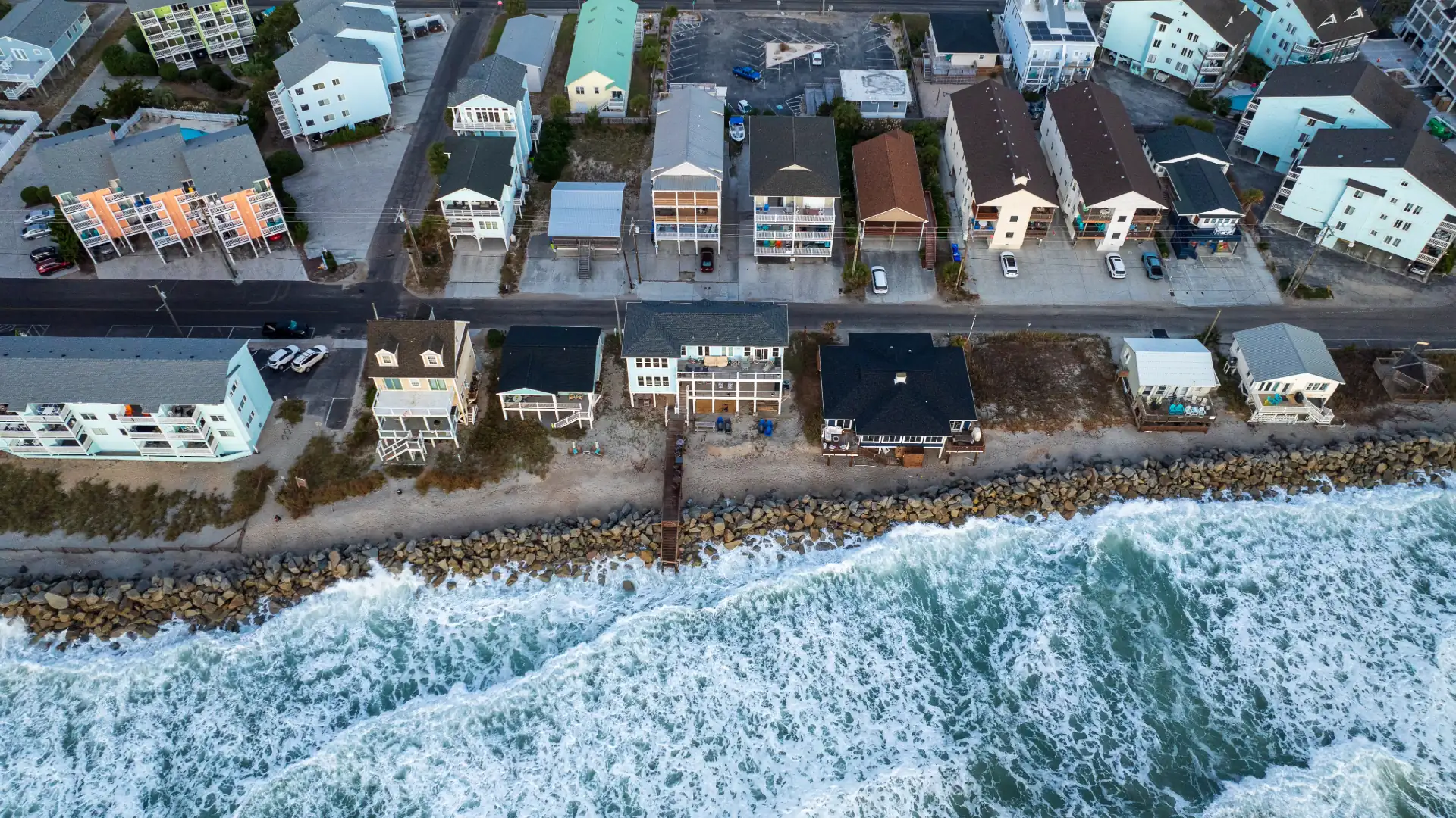Aerial view of storm surf pounding the shoreline in front of coastal homes