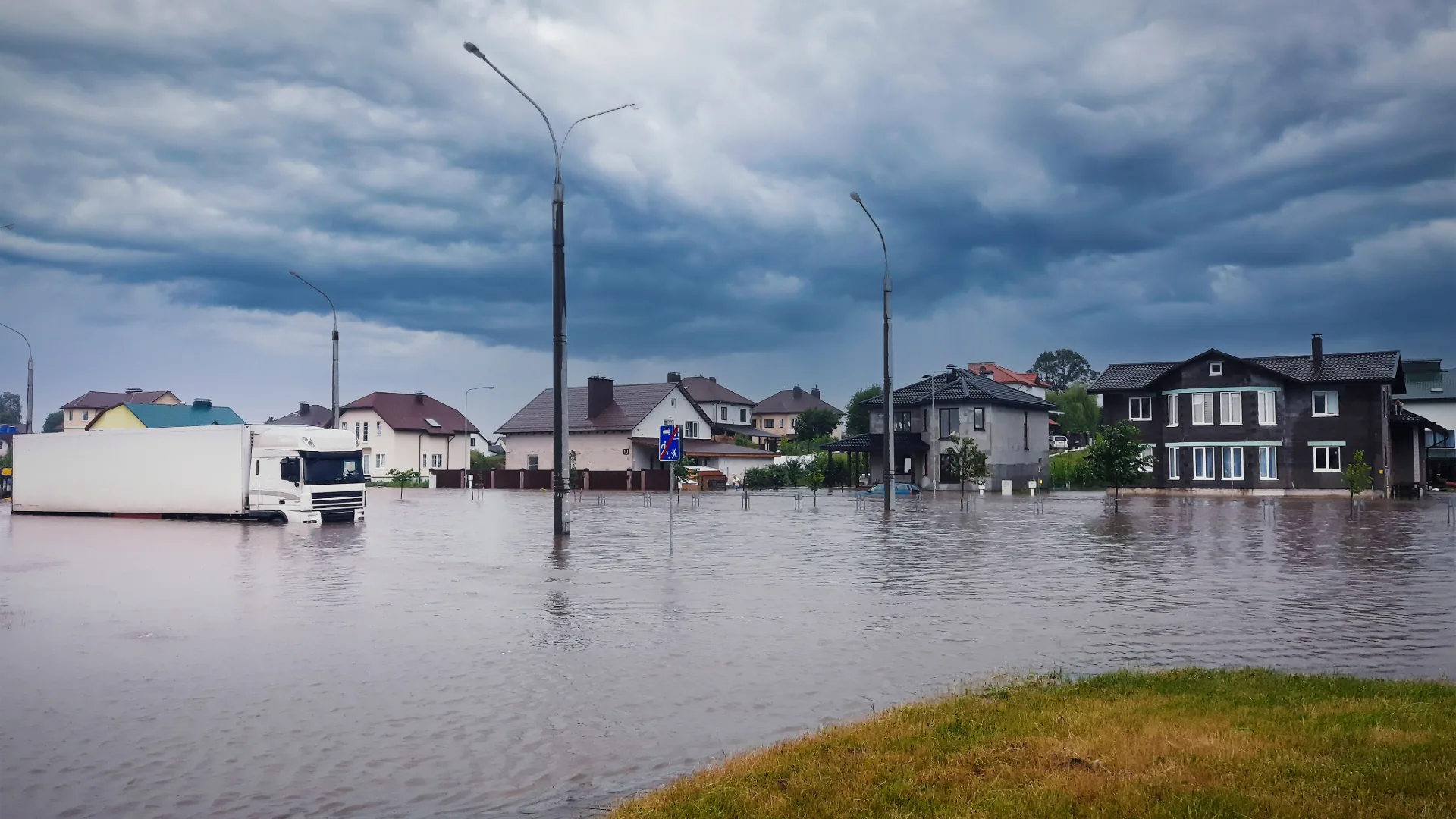 Flooded neighborhood street and homes under a heavy storm sky