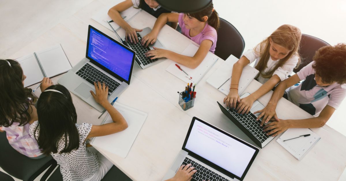 A diverse group of kids working together on a laptop, engaged in real-world problem solving for kids. This image illustrates how kids use tech with purpose and apply STEAM for problem solving in a collaborative setting.