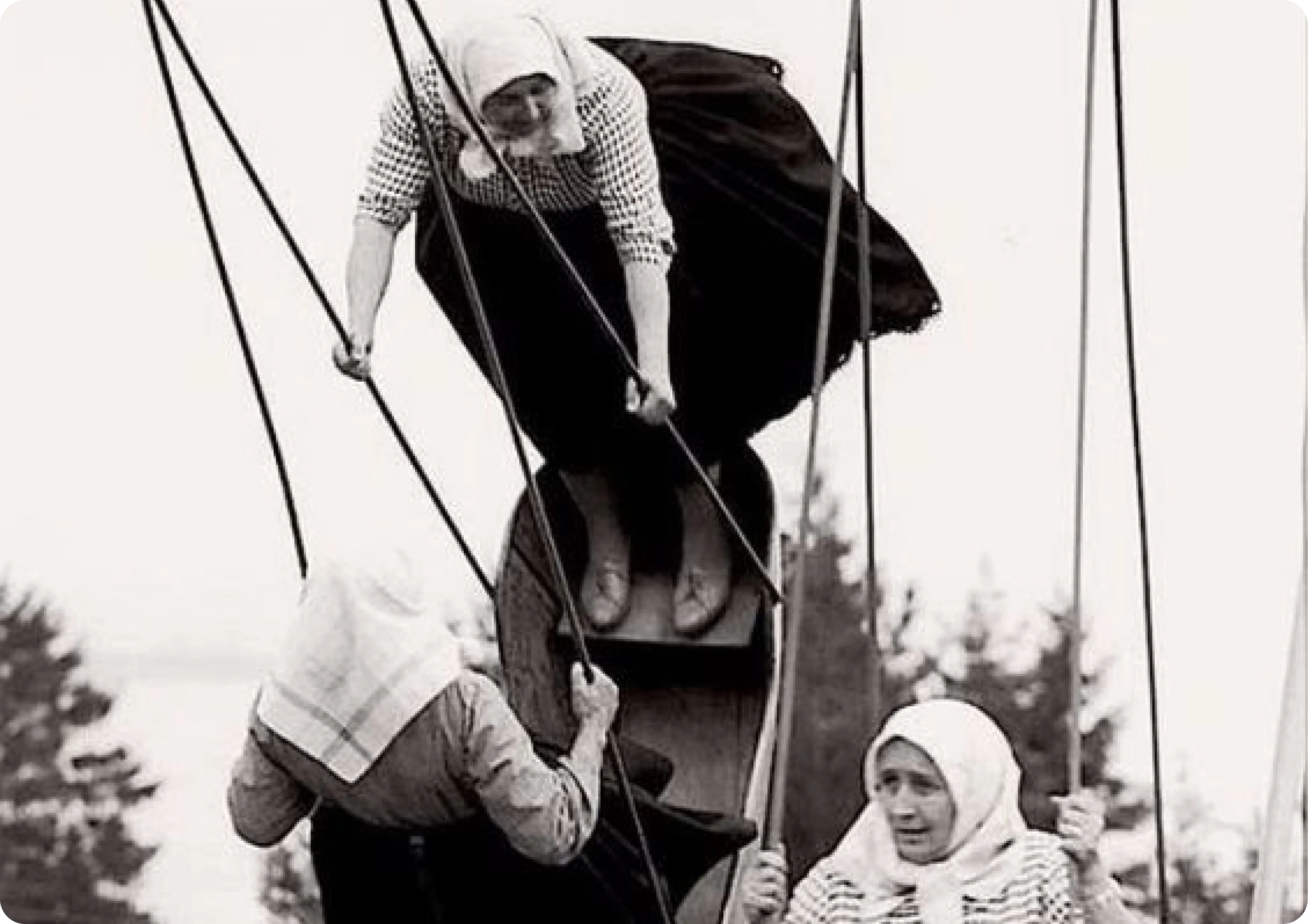 Women in traditional clothing on a swing.