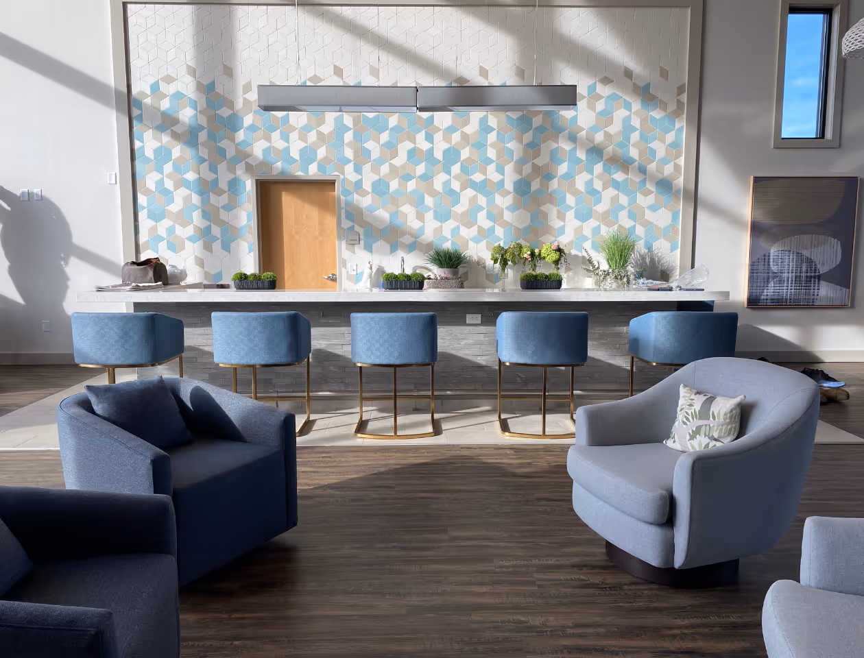 The Honeycutt Country Club area was designed by Stacy Nicole Interiors, offering a comfortable and inviting space.- A blue chair in a room with a blue and white wall. Stacy Nicole Interiors is a full-service North Carolina interior design firm. Luxury interior design in Charlotte-based at 1515 Mockingbird Lane, Suite 420, Charlotte, NC 28209. SouthPark luxury interiors.