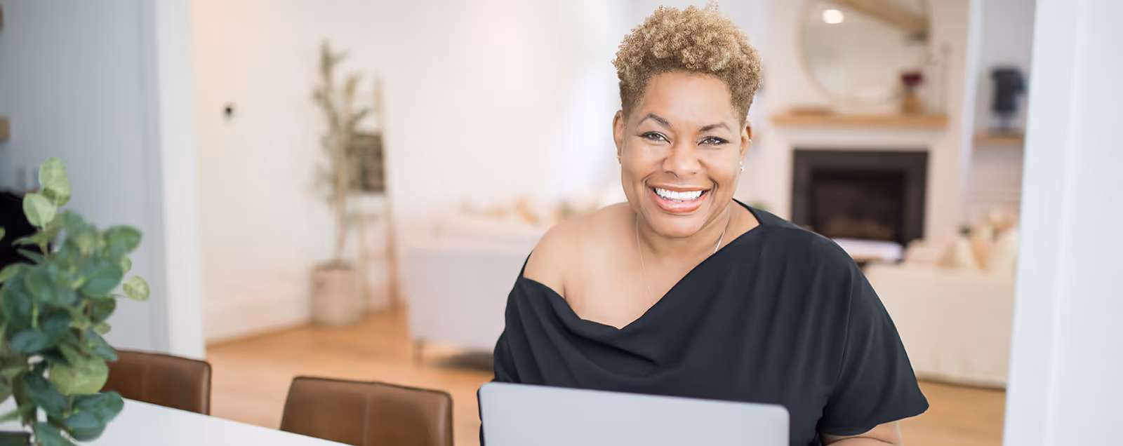 Black north carolina interior designer Nicole Ingram with a laptop and a brown chair. Stacy Nicole Interiors is a full-service North Carolina interior design firm. Luxury interior design in Charlotte-based at 1515 Mockingbird Lane, Suite 420, Charlotte, NC 28209