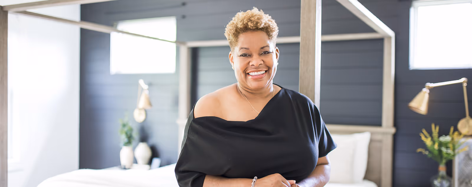 Nicole S. Ingram, CEO + Principal Designer at Stacy Nicole Interiors,  wearing a black shirt and a bracelet is smiling.  Stacy Nicole Interiors is a full-service North Carolina interior design firm. Foxcroft elegant interiors.