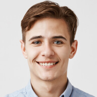 A man with a blue shirt and tie smiling.