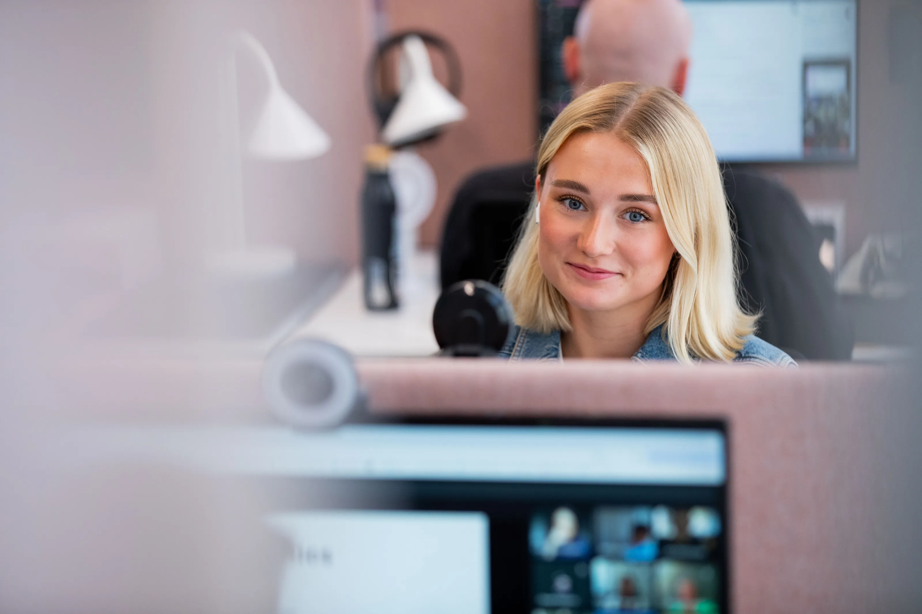Employee smiling at her desk behind a computer screen
