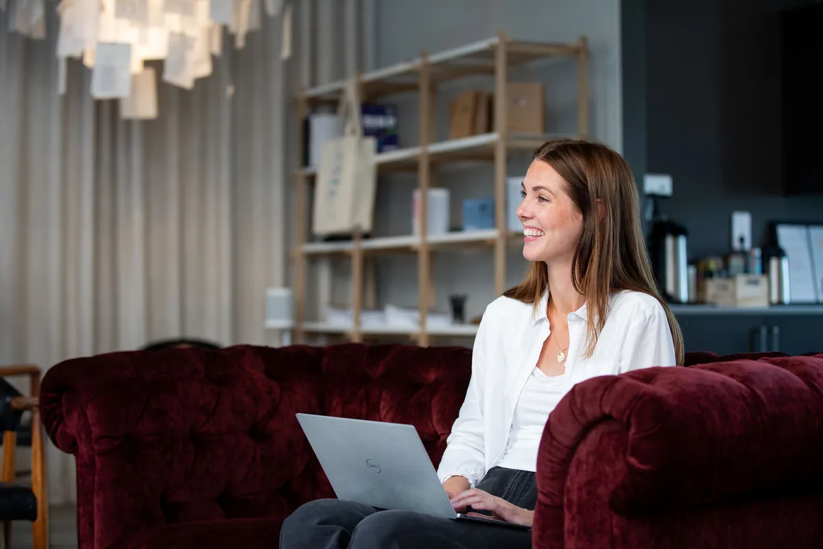 Employee working on a laptop on a sofa in the office