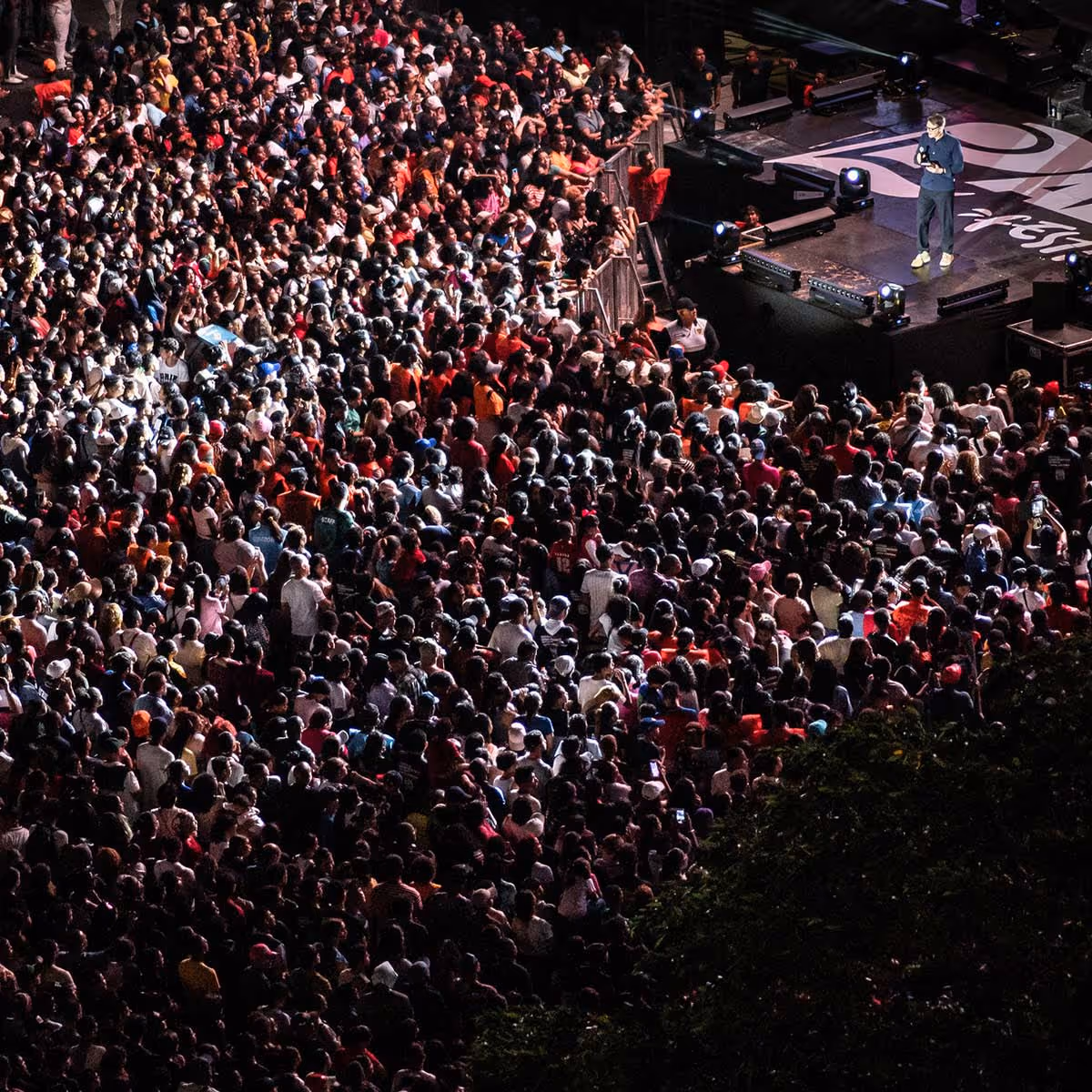 An aerial view of a large event with a man on stage speaking to the crowd