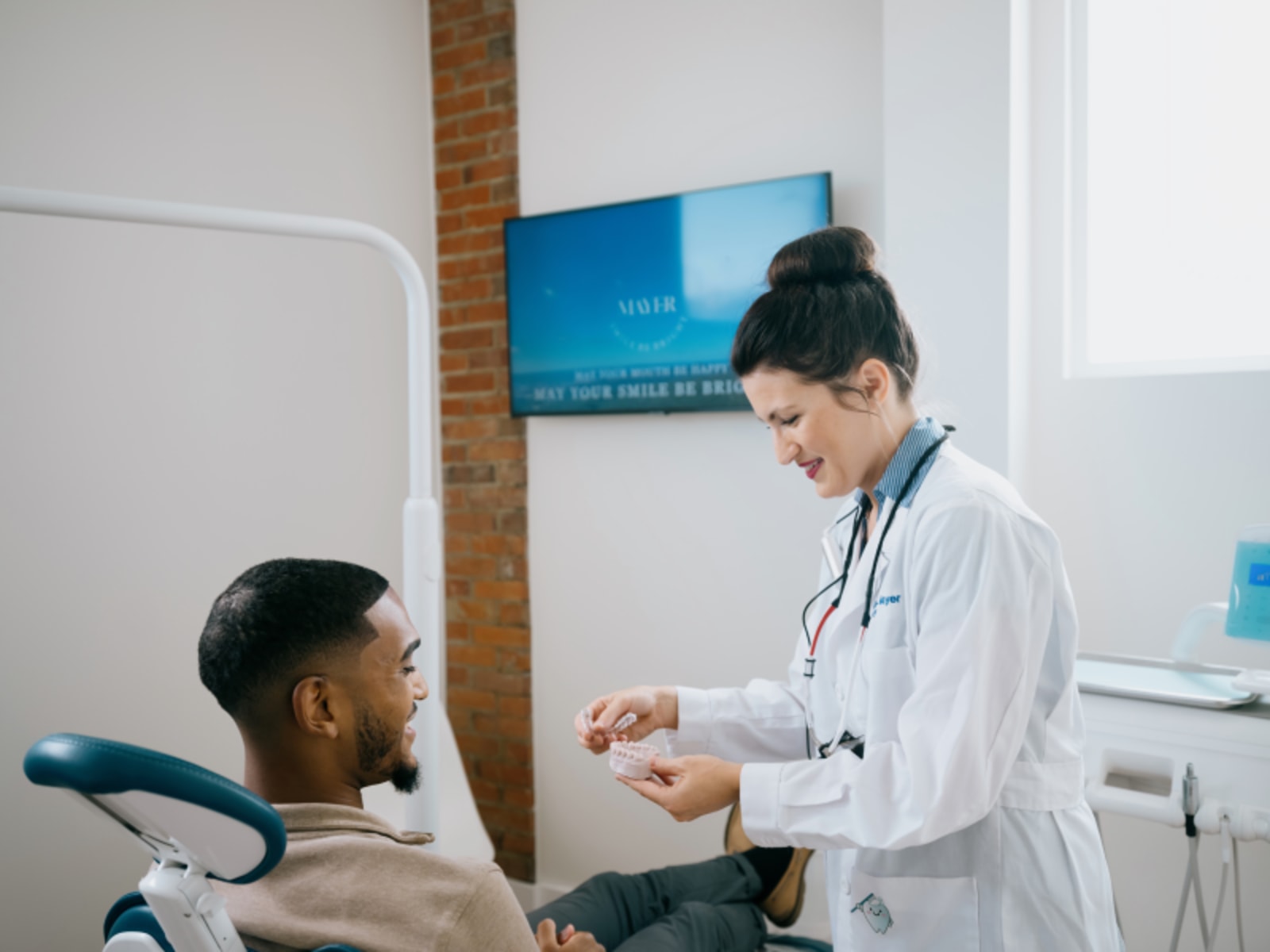 Dentist consulting with male patient in clinical treatment room