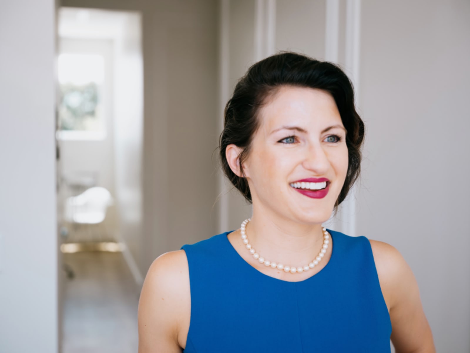 Woman in blue dress standing in modern dental office hallway with bright, welcoming atmosphere