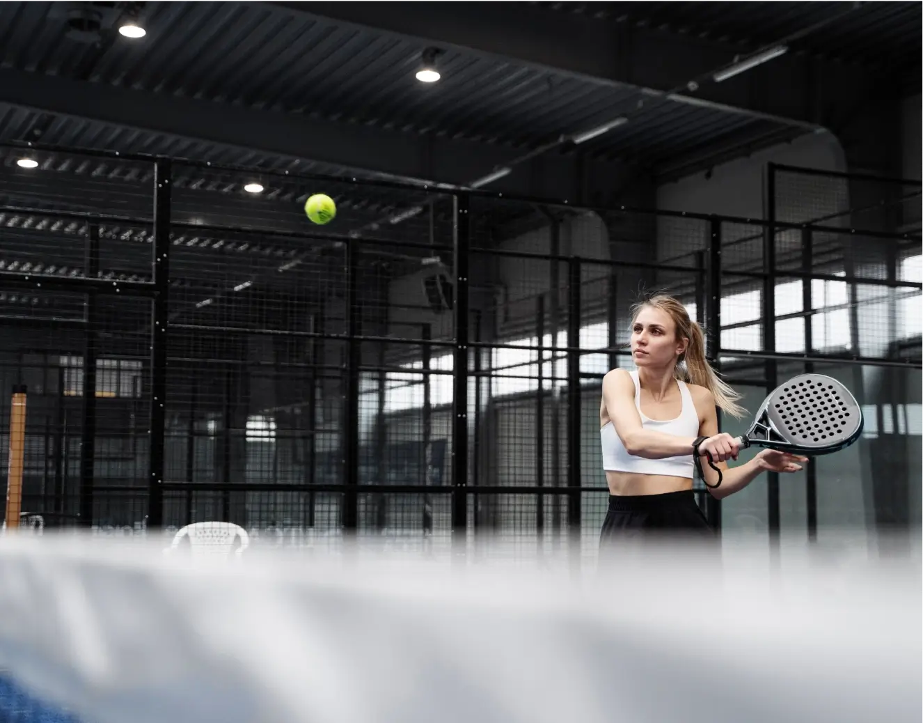 Blonde, female padel player swinging the padel racket.
