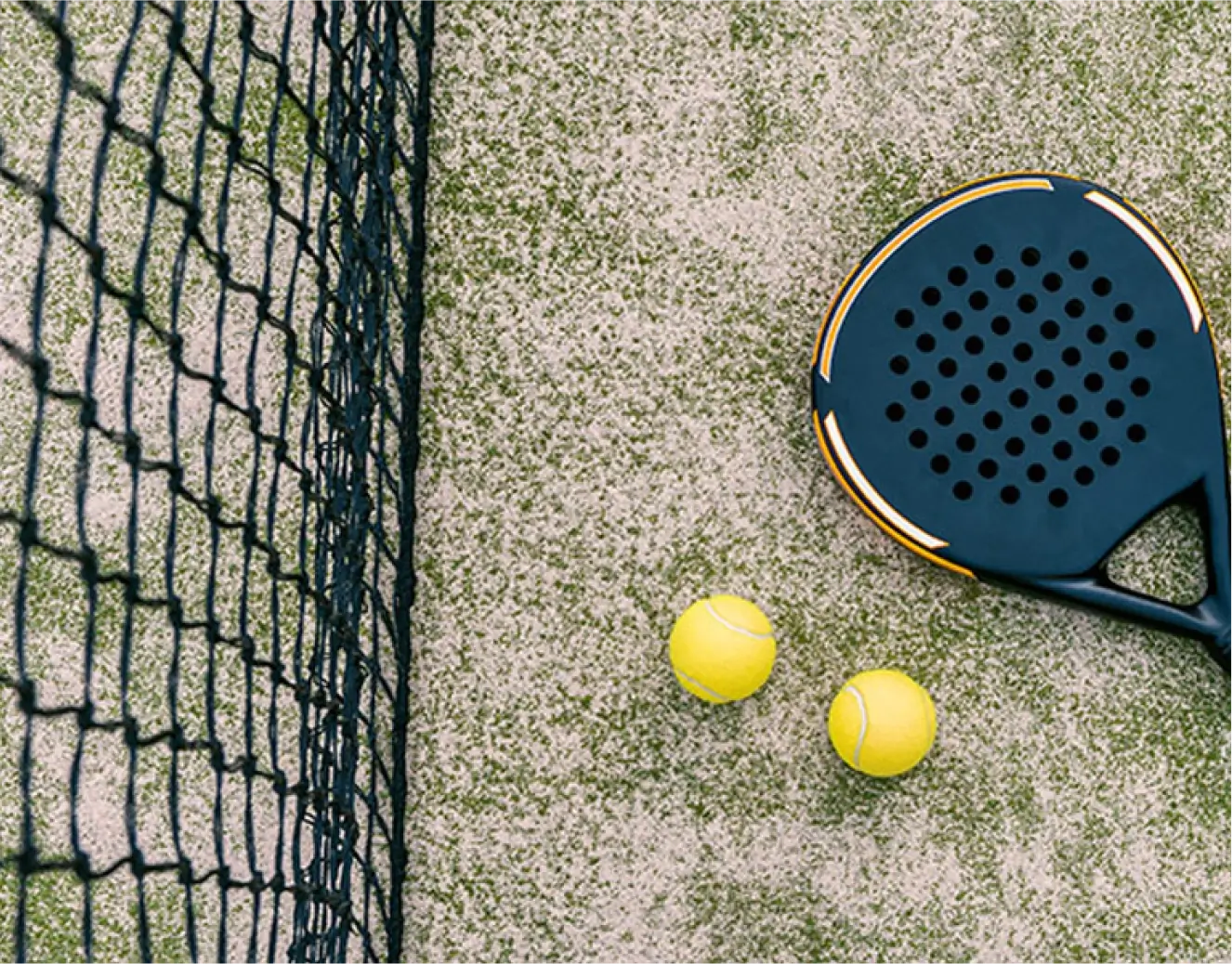 Padel racket on the floor with two balls by the side of the net