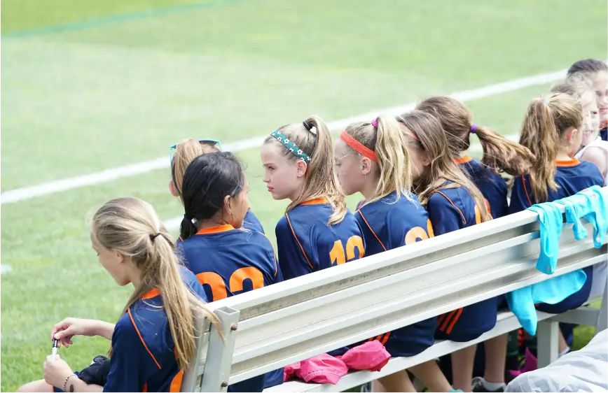 School children sitting on bench watching tennis