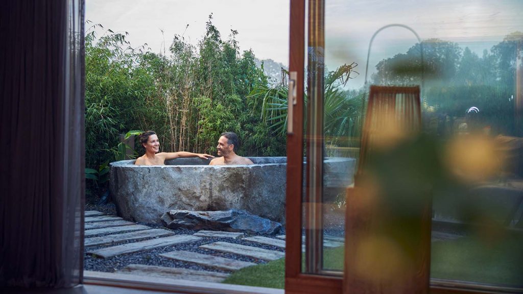 Auf der Terrasse in der Nähe des Bali-Raums im Fort Resort Beemster sitzen Menschen, die ein Schaumbad genießen.