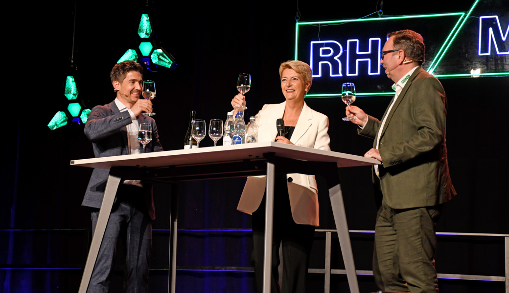 Bundesrätin Karin Keller-Sutter hat Moderator Tobias Müller (links) und Tagungsleiter Ralph Dietsche ein Glas Weisswein eingeschenkt. (Bild: Monika von der Linden, «Der Rheintaler»)