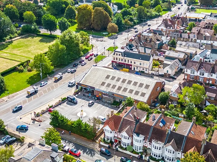 Aerial view of a landscape with a section of clear-cut forest next to dense green pine trees and grassy land in the foreground.
