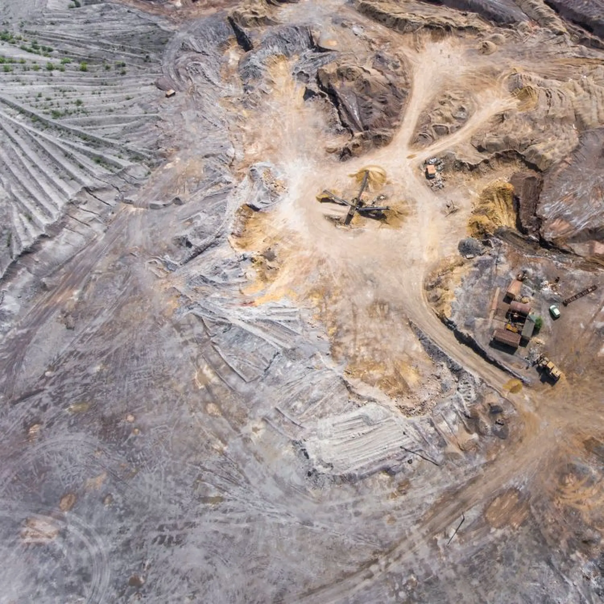 Aerial view of a mining site with excavation areas, machinery, and dirt roads.