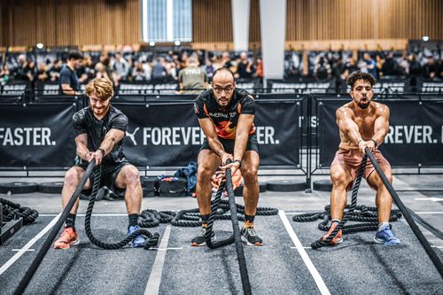 Trois participants sur la station du sled pull lors d'un HYROX