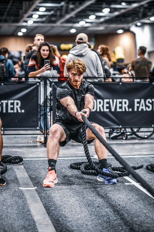 Participant tirant le traineau sur la station du sled pull d'une course HYROX
