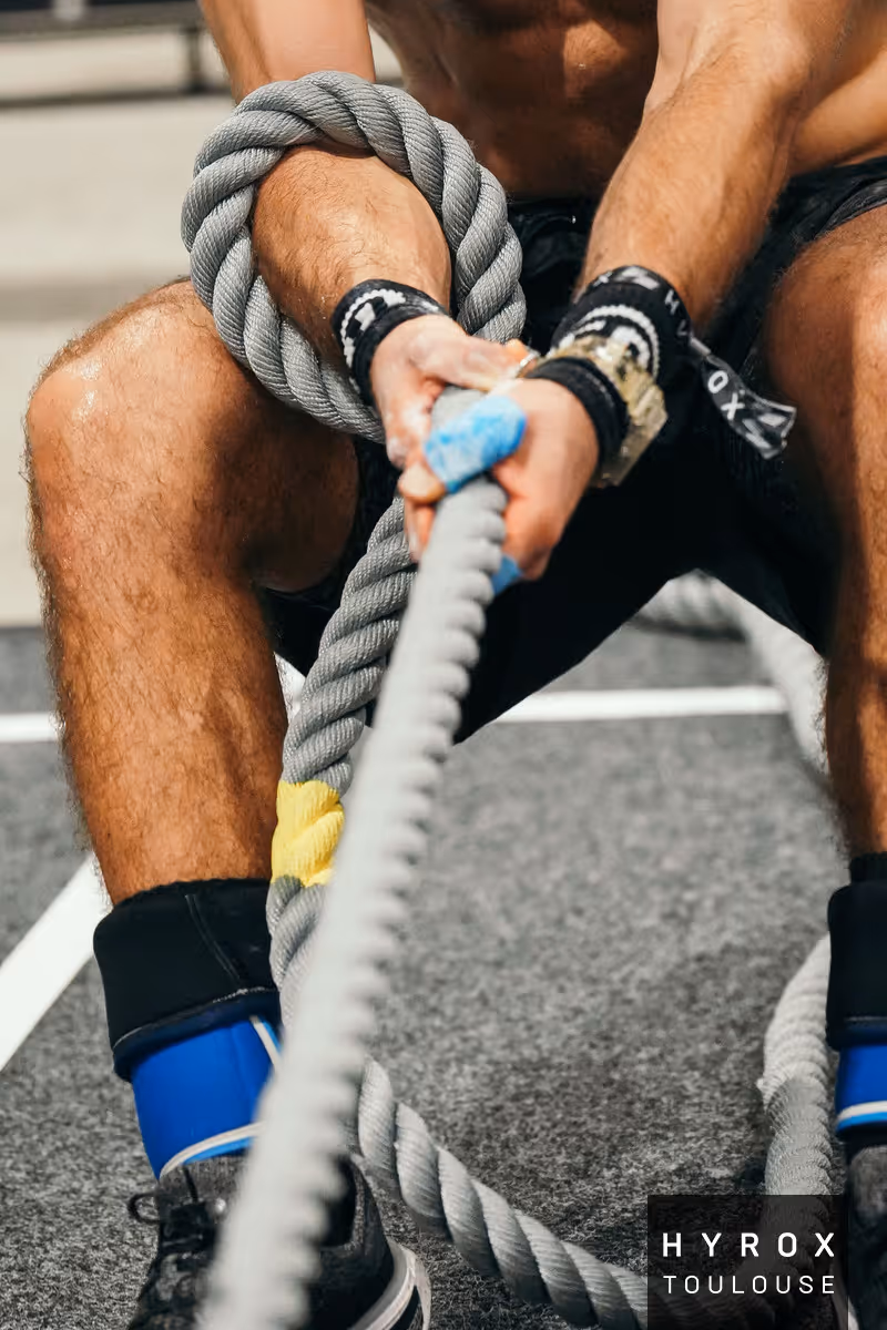 Gros plan sur les mains d'un participant sur la station du sled pull d'une course HYROX 