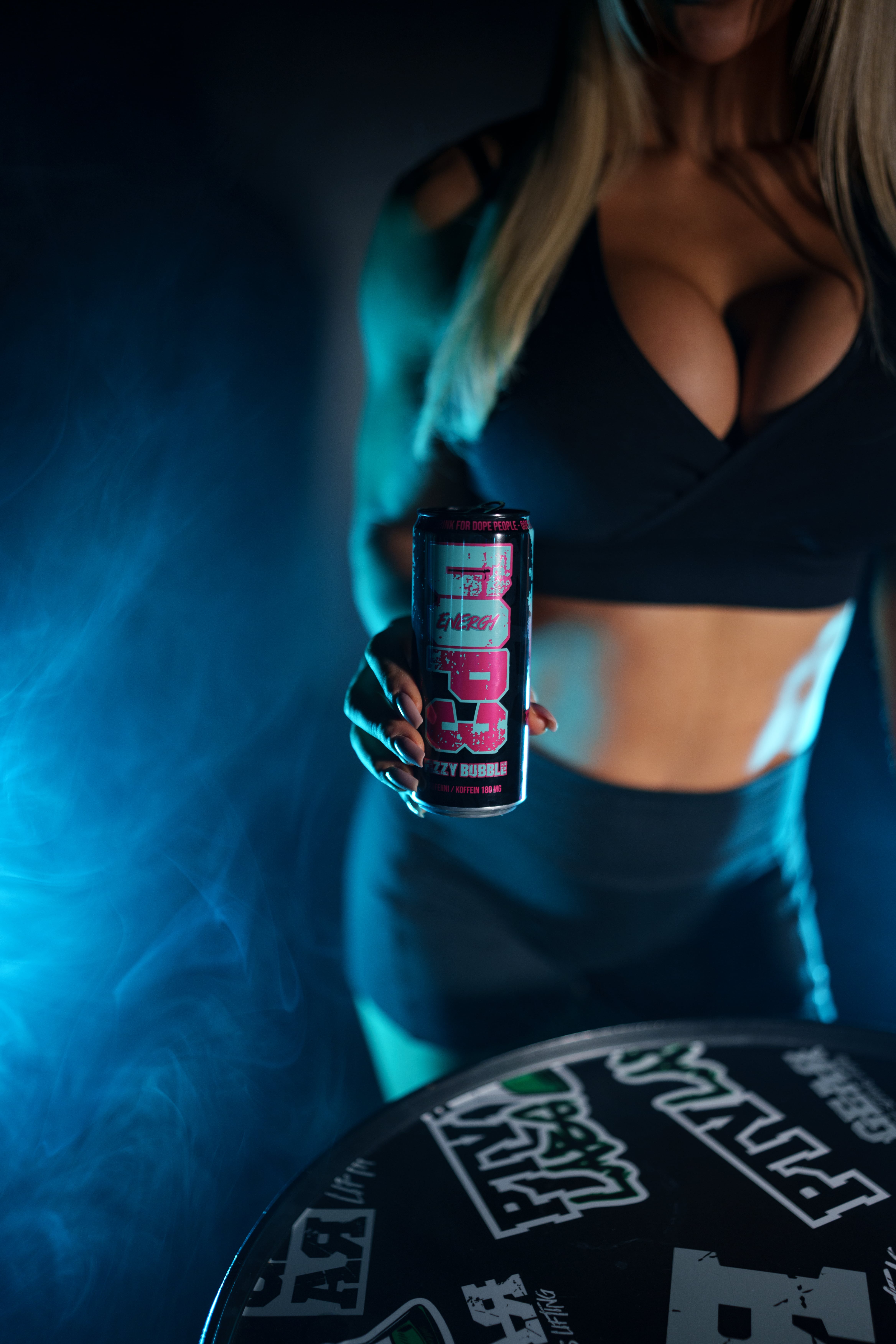 Woman holding a DOP3 Energy can in a dark setting with blue lighting and smoke