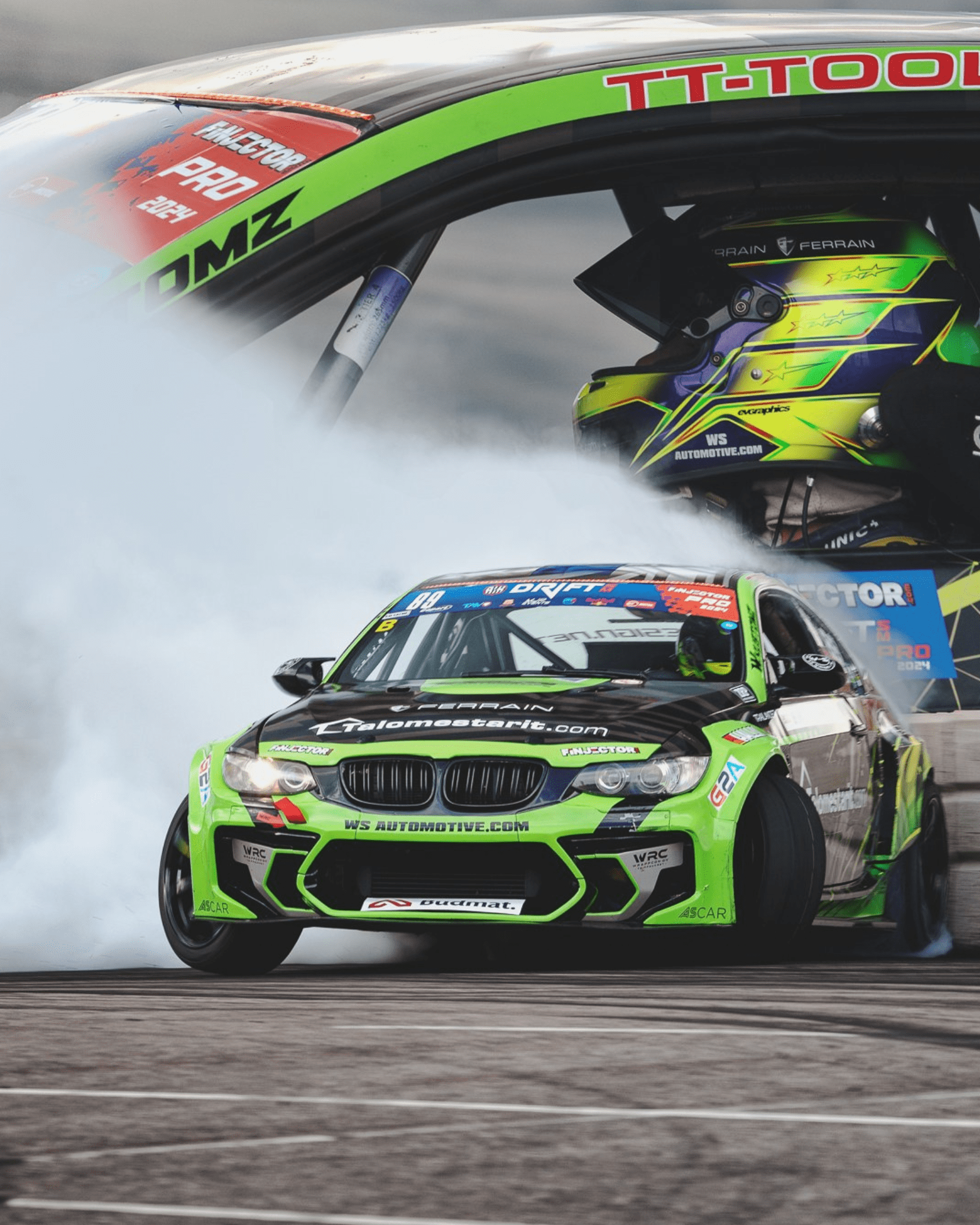 Green and black BMW drifting on a race track with smoke trailing behind and a driver wearing a matching helmet.