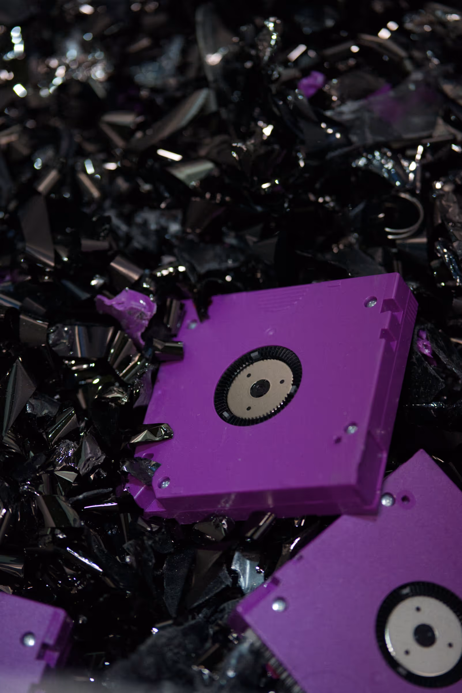 Zerstörte Magnetbandkassetten mit violettem Gehäuse, umgeben von zerfetztem schwarzem Magnetbandmaterial