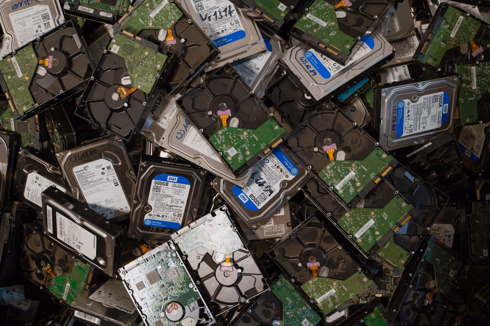 Große Menge gebrauchter Computer-Festplatten mit sichtbaren Aufklebern und Platinen