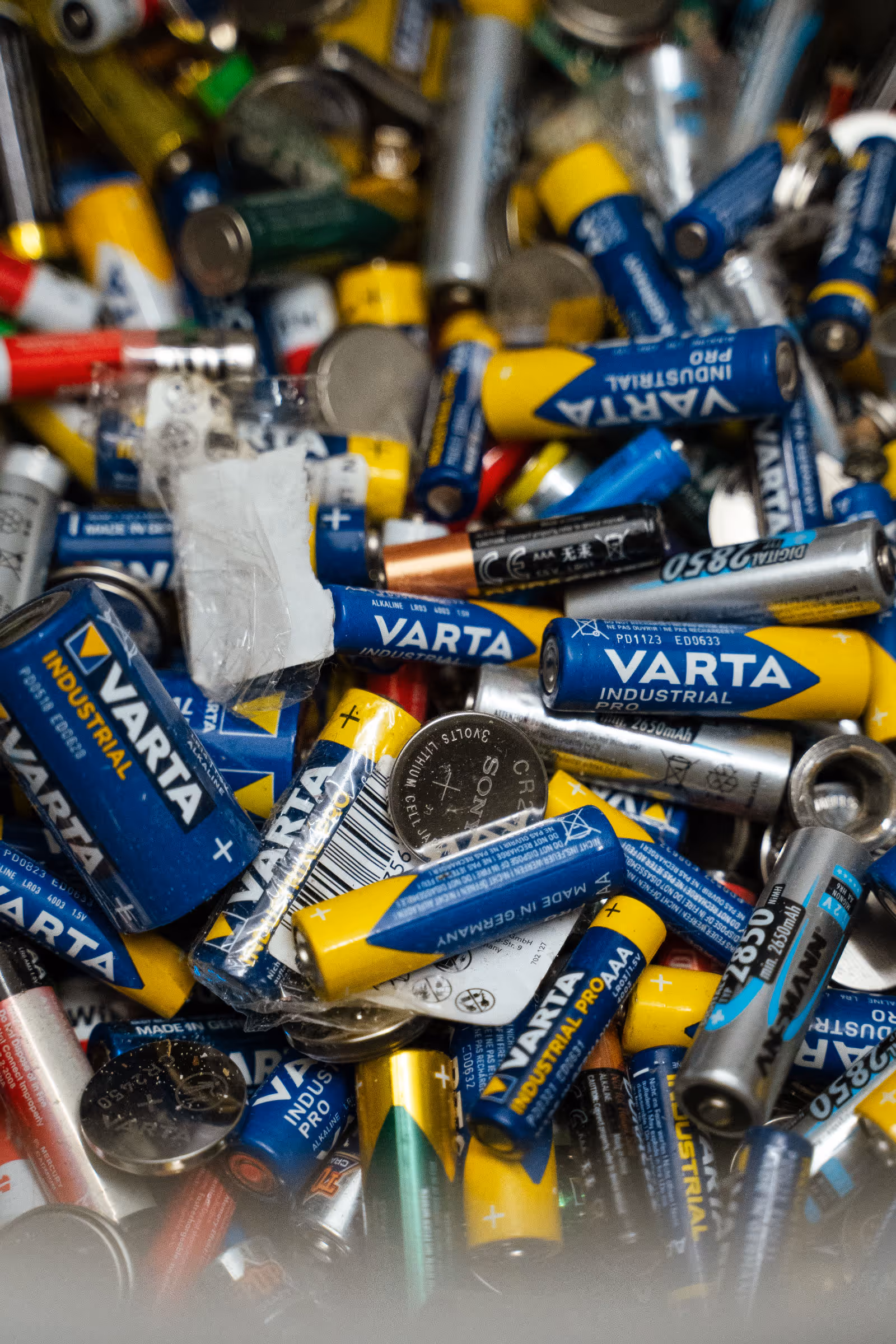 Sammlung gebrauchter Haushaltsbatterien verschiedener Marken und Formate, unsortiert in einer Kiste