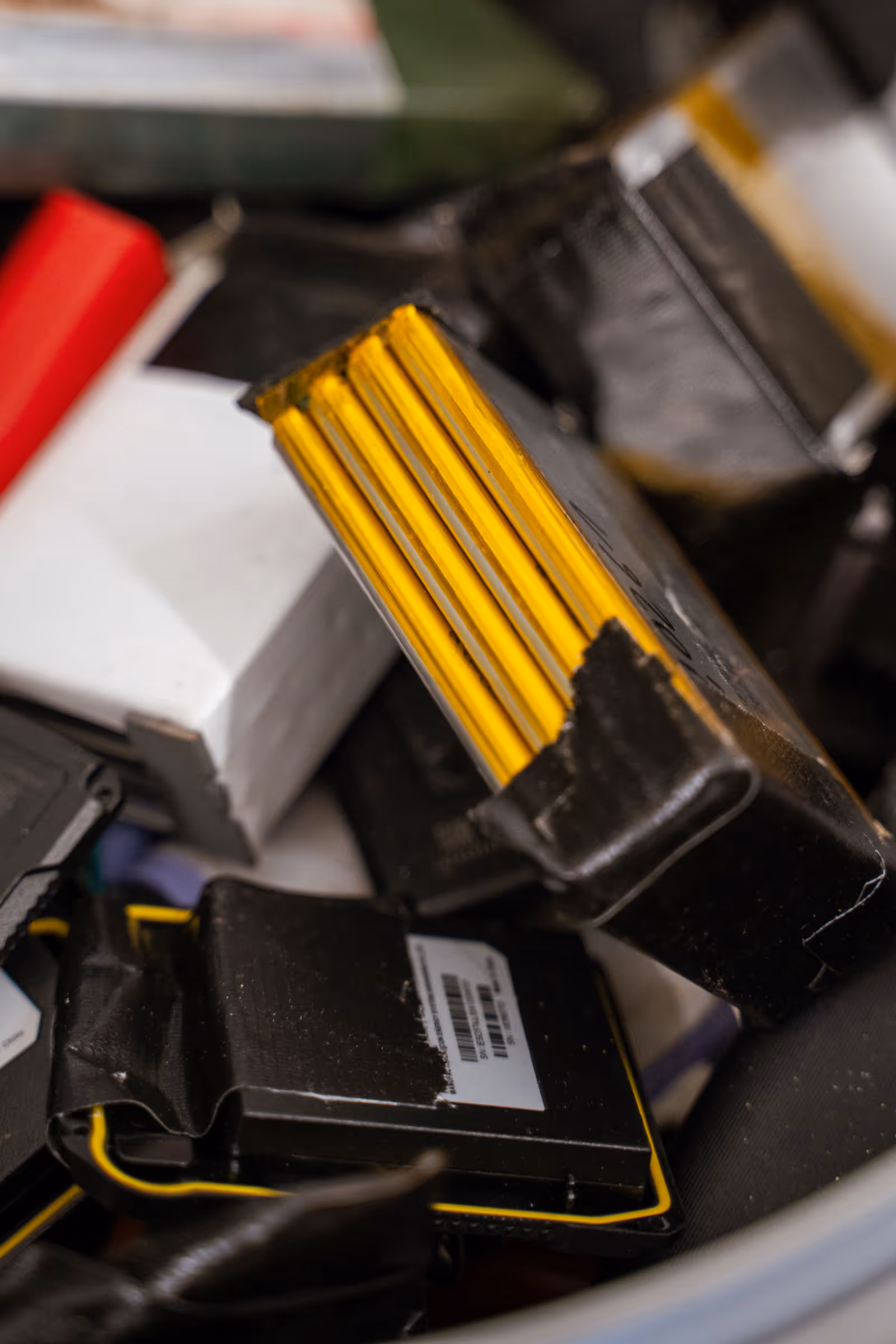 Gebrauchte Lithium-Ionen-Akkus mit teilweise sichtbaren gelben Zellpaketen und beschädigten Kunststoffgehäusen